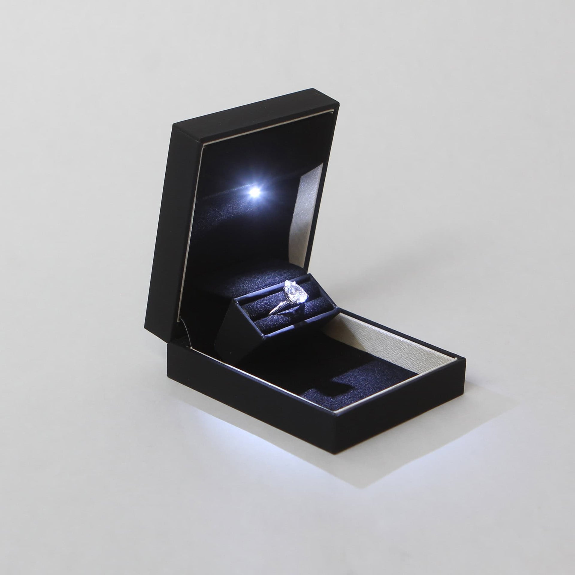 pocket sized slim discreet black proposal ring box for proposals and engagements with pear shaped diamond engagement ring lit up by a built in LED light