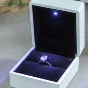white wedding ring box with oval diamond engagement ring and LED light