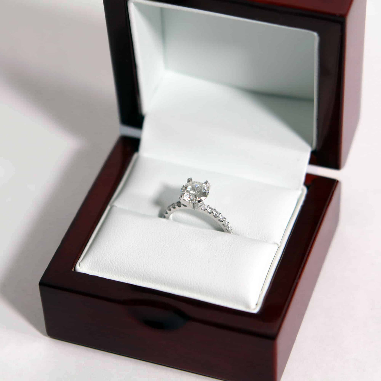 closeup of diamond proposal ring in a classic rosewood ring box with white leather