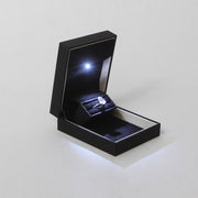 pocket sized slim discreet black proposal ring box for proposals and engagements with pear shaped diamond engagement ring lit up by a built in LED light